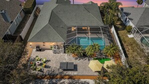 Vista aérea de una propiedad residencial con piscina, mobiliario de exterior y jardín ajardinado.