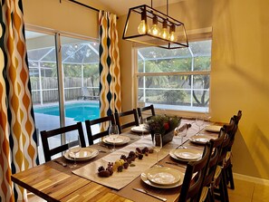 Enjoy meals in this dining area with a table for four, surrounded by a floral arrangement and a pine cone garland.