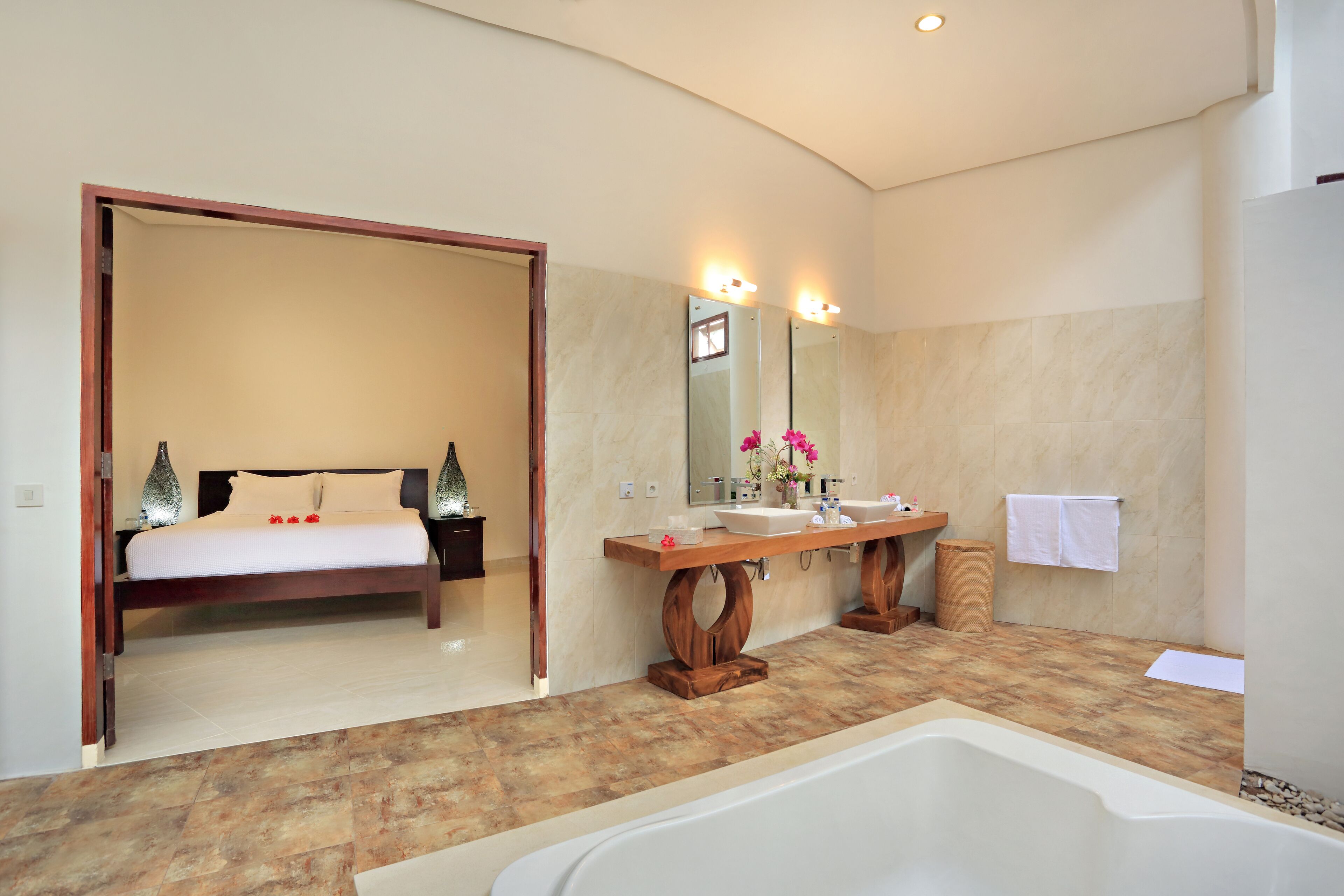 A modern bathroom with a large bathtub, wooden vanity, and a mirror with lights.