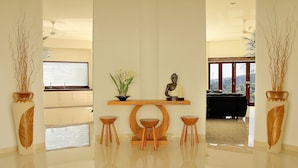 A modern interior with a wooden console table, a Buddha statue, and two stools. - Villa Kipas Retreat (Senggigi)