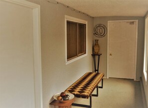 A hallway with a bench, a door, and a wall-mounted decorative item.