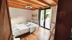 A single bed with a white mattress and a quilt, a wooden ceiling, and a sliding glass door leading to an outdoor area. - Villa with pool in Pelekas near the beach (Pelekas)