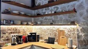 A kitchen with wooden shelves, a stone backsplash, and various kitchen appliances. - Villa with pool in Pelekas near the beach (Pelekas)