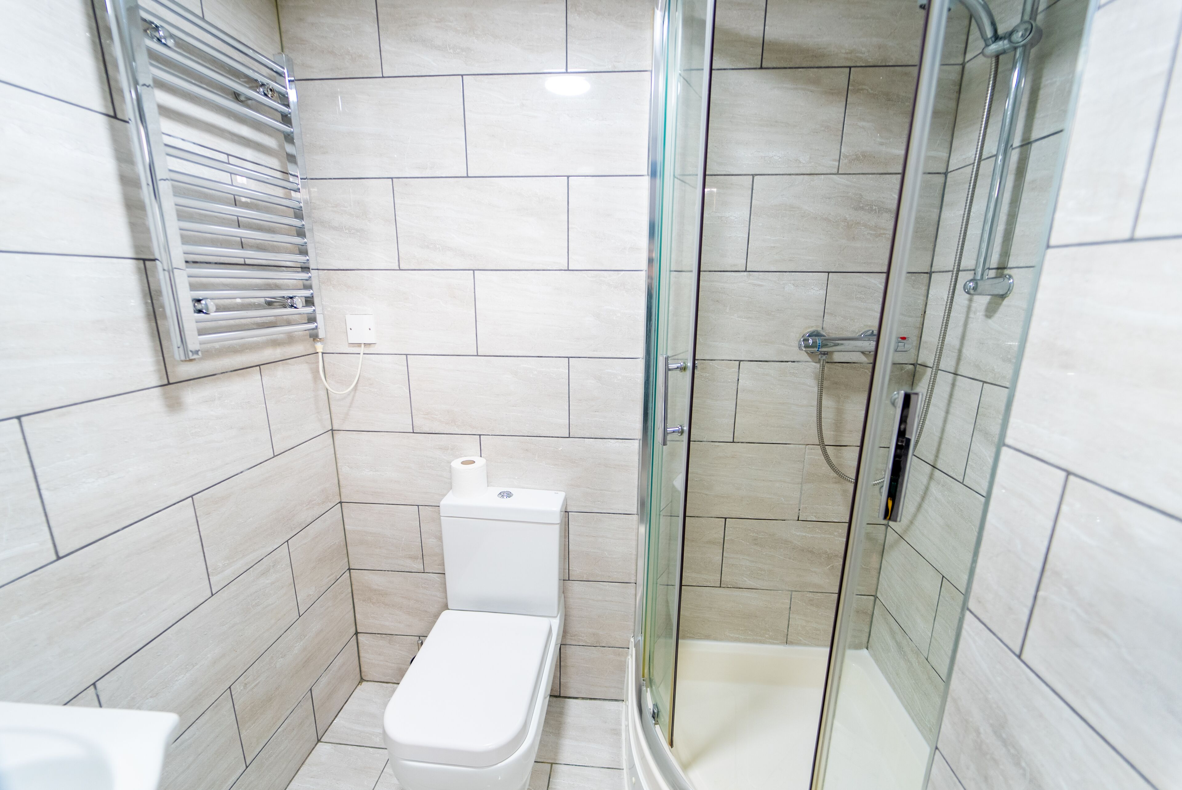 A bathroom with a toilet, a glass-enclosed shower, and a towel rack.