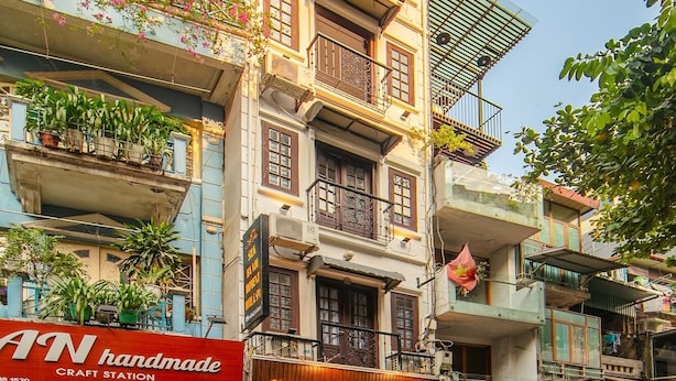 Un immeuble à plusieurs étages doté de balcons, d’un espace dédié aux activités manuelles et d’une enseigne d’hôtel.