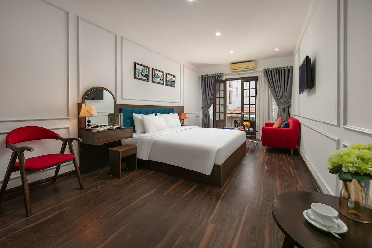 Een hotelkamer met een groot bed, een bureau met een stoel, een televisie en uitzicht op de stad door het raam.