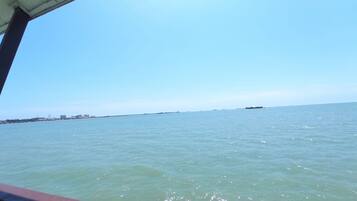 A view of a calm sea with a distant shoreline and a bridge structure.
