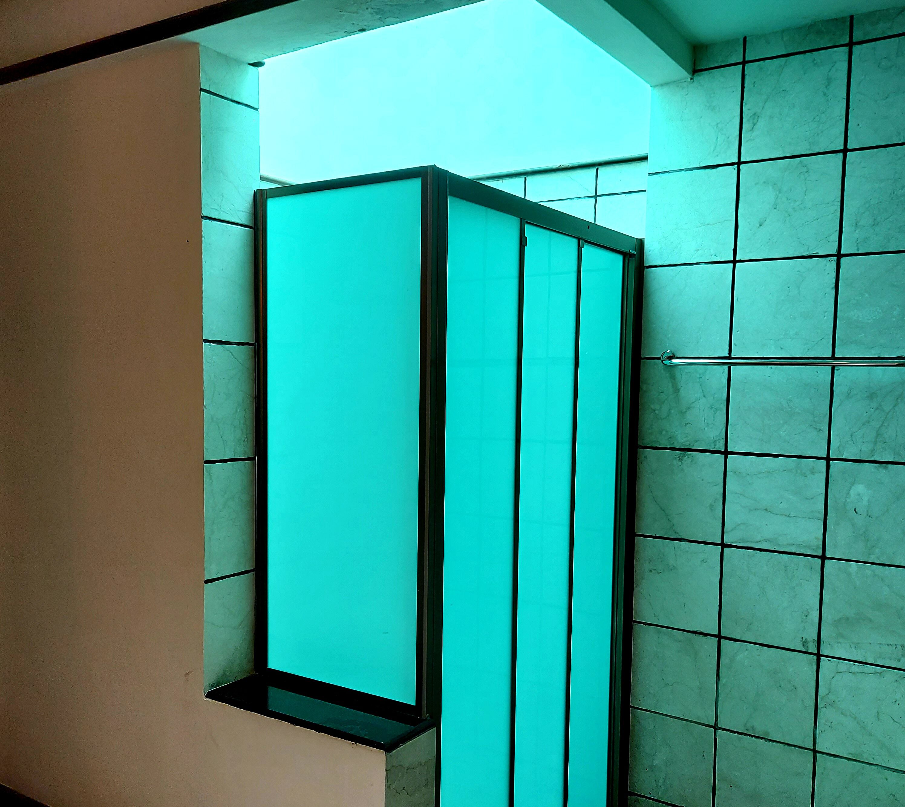 A bathroom with a teal-colored cabinet and tiled walls.