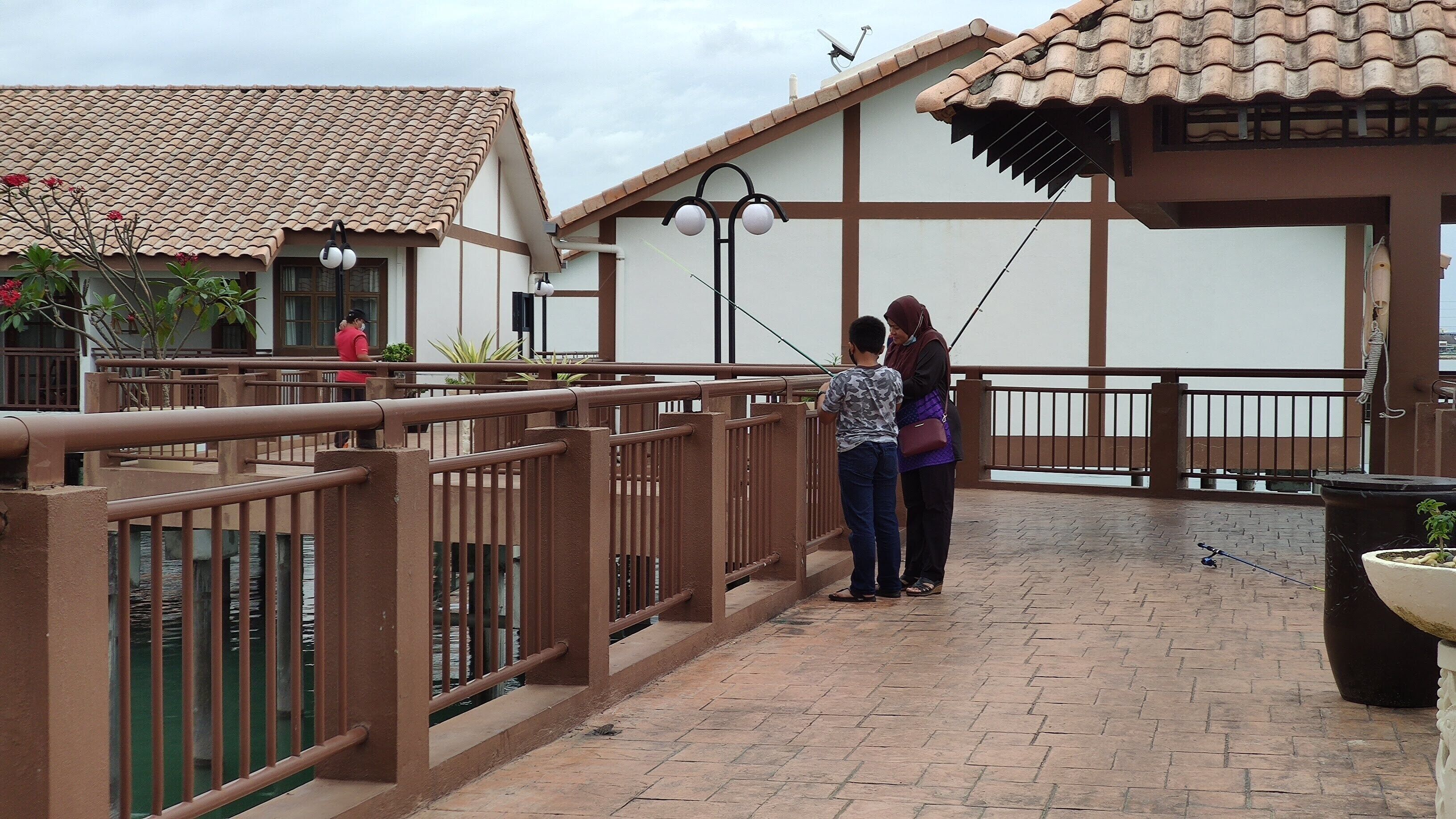 A courtyard with a tiled roof, a railing, and a potted plant.
