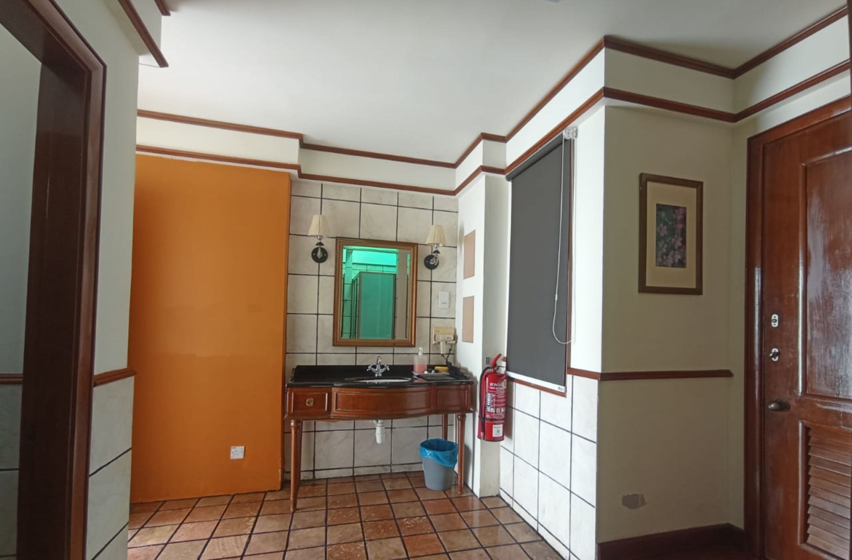 Een kleine, compacte keuken met een betegelde vloer, een spoelbak, een spiegel en een brandblusser.