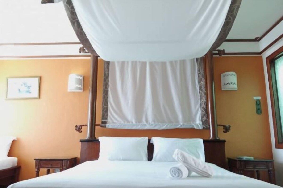 A hotel room with a canopy bed, a small table, and a nightstand.