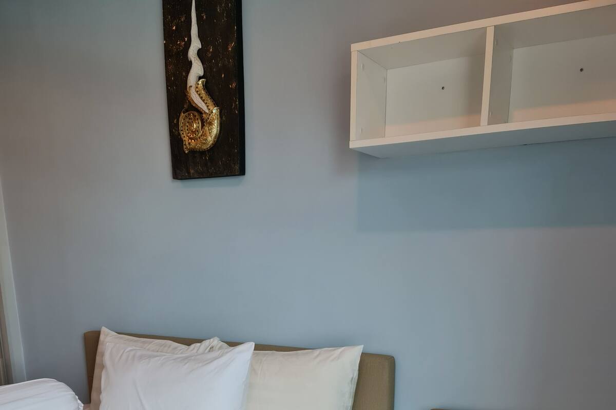 Una habitación de hotel con cama, sofá y estante en la pared.