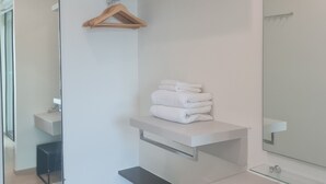 Un baño moderno con un espejo grande, un perchero para toallas y un estante con toallas dobladas.