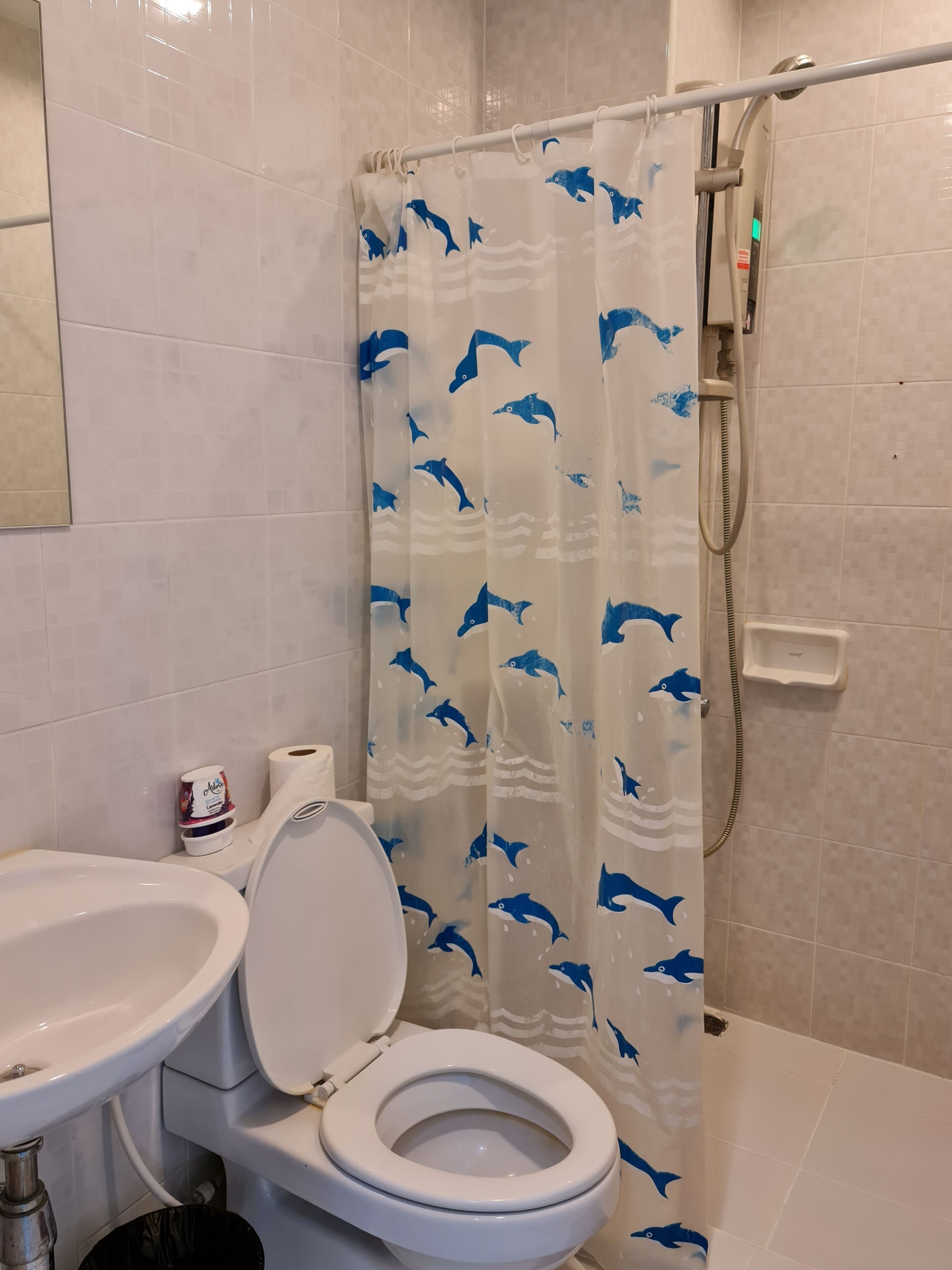 Ett badrum med toalett, handfat och duschdraperi med delfinmotiv.