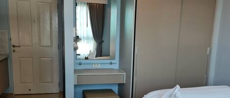A hotel room with a bed, a mirror, a wardrobe, and a small bench.