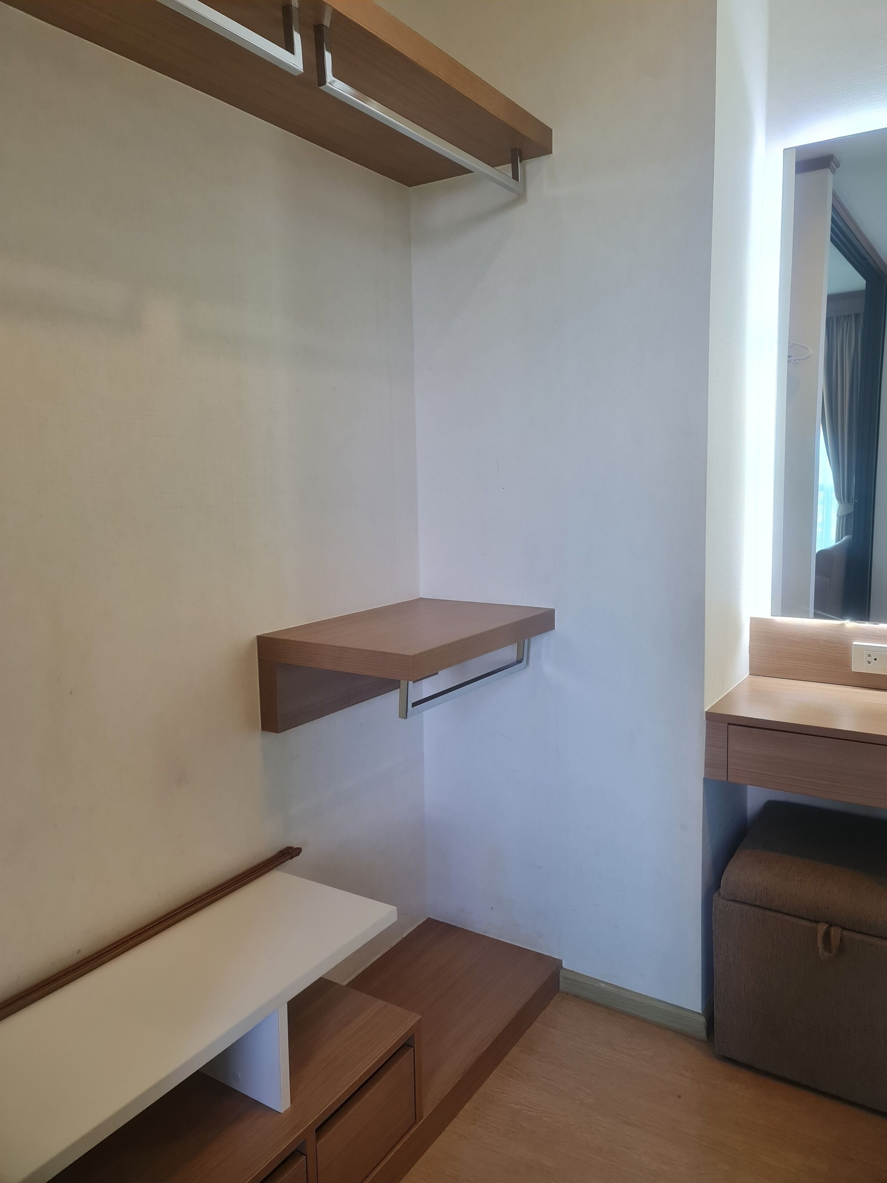 A corner room with built-in wooden shelves, a bench, and a small desk.
