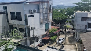 Un edificio moderno con piscina, rodeado de vegetación y un cielo despejado.