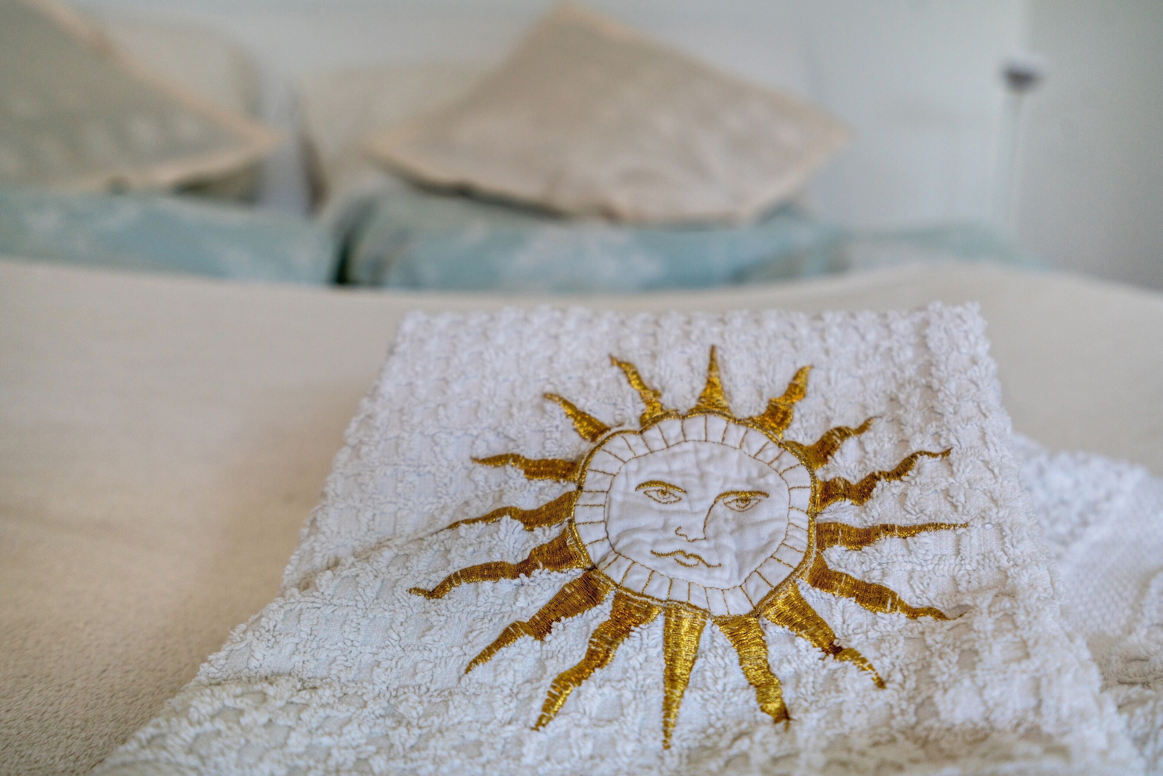 Un letto con una coperta bianca e un asciugamano con un motivo a sole.