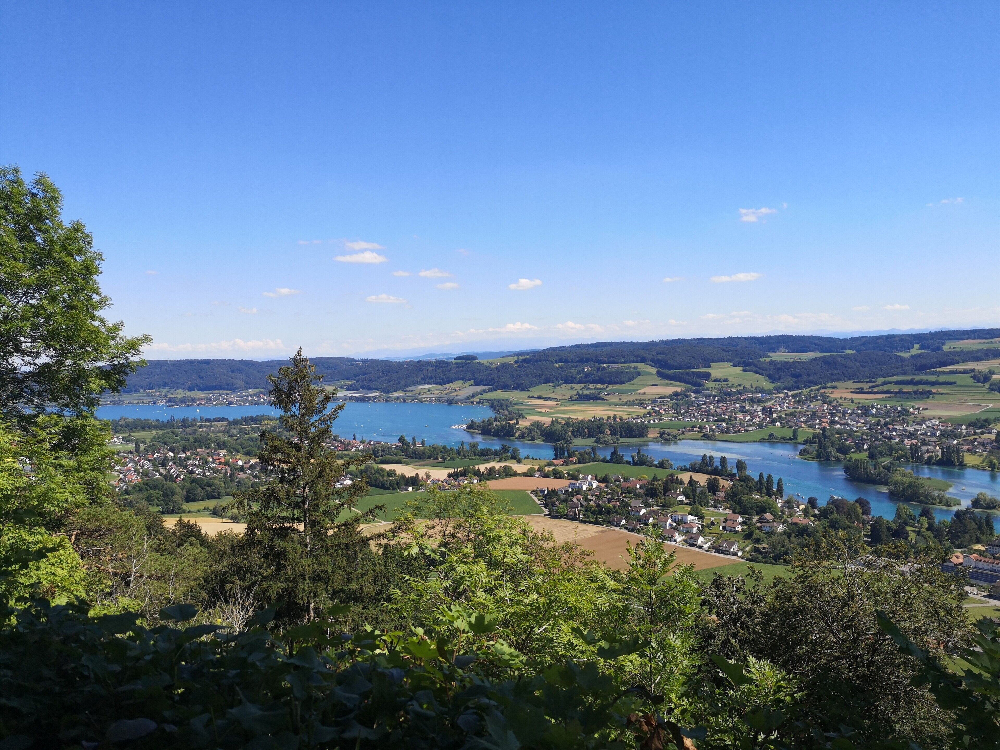 Une vue panoramique d’une ville traversée par une rivière, entourée de verdure et de collines.