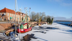 A harbor with boats docked, a brick building, and a clear sky. - Holiday Apartment "Nordsee 1" with Shared Terrace, Shared Garden & Wi-Fi (Wangerland)