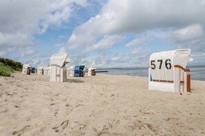 Deux chaises de plage, numérotées 576 et 578, sont installées sur une plage de sable, avec la mer en arrière-plan.