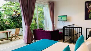 Un dormitorio con cama, televisor, cuna y vistas al exterior.