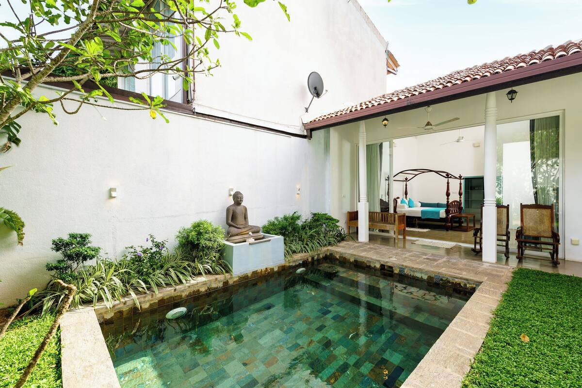 Ein ruhiger Poolbereich mit einer Buddha-Statue, üppigem Grün und einer gemütlichen Sitzgelegenheit mit einer Schaukel.
