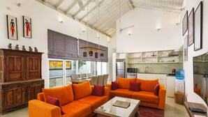 Un salón amplio con sofás naranjas, un aparador de madera y un ventanal grande.