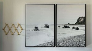 Two framed black and white photographs of a beach scene with rocks and waves, mounted on a white wall. - Ocean View Studio Near LA Stadium & LAX | Balcony (Manhattan Beach)