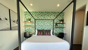 A modern bedroom with a large bed, a tufted bench, and a green leaf-patterned wallpaper. - Ocean View Studio Near LA Stadium & LAX | Balcony (Manhattan Beach)