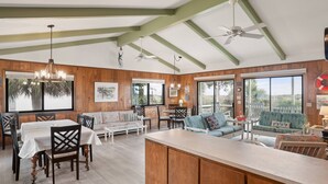 A spacious kitchen with wooden cabinets, a central island, and a dining area with chairs and a table. - "Fant-A-Sea": Oceanfront Escape with Stunning Views, Screened Porch, Deck & Beach Access! (Saint Helena Island)