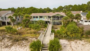 A beachfront property with a wooden walkway leading to a house with multiple windows and a balcony. - "Fant-A-Sea": Oceanfront Escape with Stunning Views, Screened Porch, Deck & Beach Access! (Saint Helena Island)