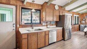 A modern kitchen with wooden cabinets, stainless steel appliances, and a window overlooking a residential area. - "Fant-A-Sea": Oceanfront Escape with Stunning Views, Screened Porch, Deck & Beach Access! (Saint Helena Island)