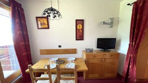 Een eethoek met een houten tafel, stoelen, een televisie en een decoratieve lamp.