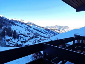 Un pueblo cubierto de nieve en la montaña, con edificios de madera y cielo despejado.