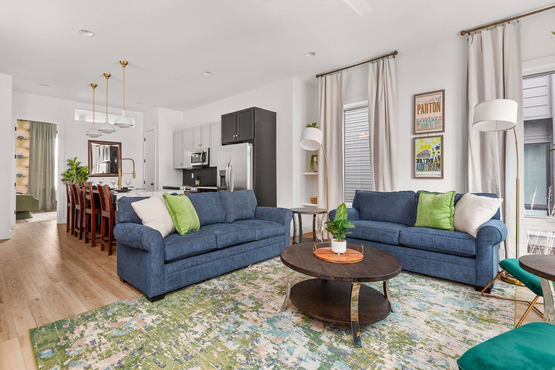 Un salon moderne avec deux canapés bleus, une table basse et un coin repas avec des chaises en bois.