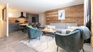 Een moderne woonkamer met een grijze bank, blauwgroene fauteuils en een houten accentmuur.