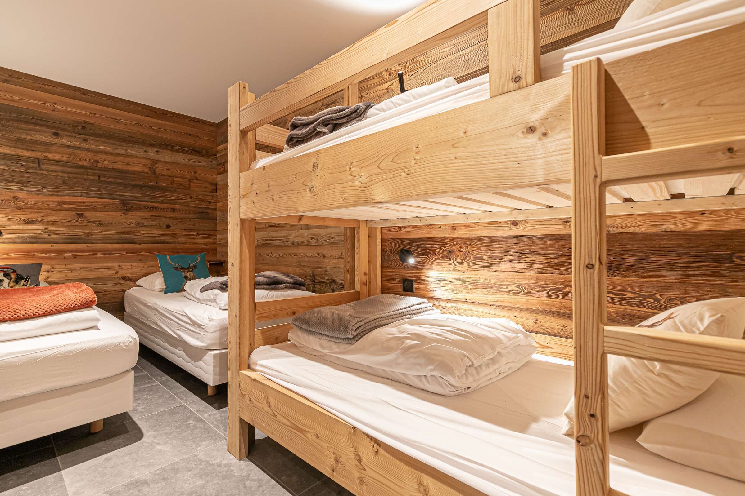 A bunk bed room with wooden walls and a separate bed.