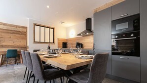 Een moderne keuken met een Bosch oven, een eettafel voor zes personen en een houten accentmuur.