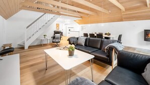 A spacious living area with a high ceiling, a staircase, a sofa set, a dining table, and a TV mounted on the wall. - "Aivars" -  from the sea by Interhome (Nørre Nebel)