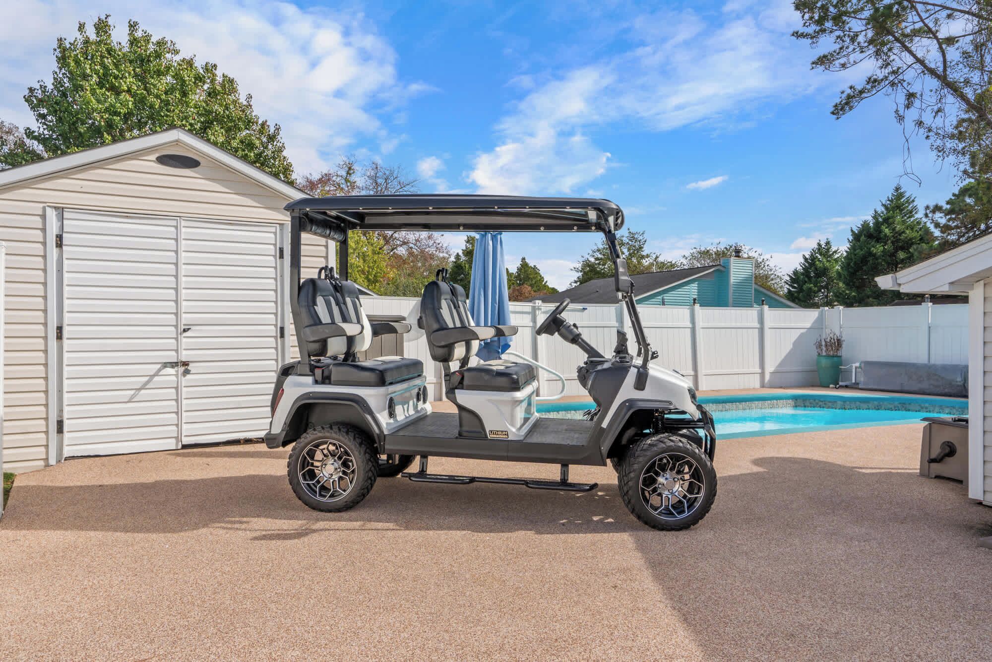A golf cart parked in a backyard with a pool and a garage.