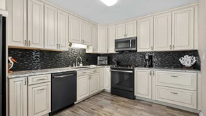 A kitchen with white cabinets, a black microwave, a black dishwasher, and a black stove. - Salty Breeze Retreat With Pool & LSV By Beach Star (Myrtle Beach)