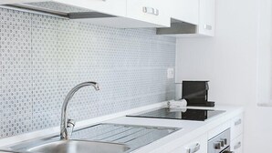 A modern kitchen with white cabinets, a stainless steel sink, and a black coffee maker. - Appartamento Sauro: A cozy apartment situated a few minutes from the town center, with Free WI-FI. (Rapallo)