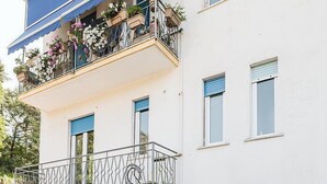 A two-story building with a covered balcony, a stone facade, and a parking area with two cars. - Appartamento Sauro: A cozy apartment situated a few minutes from the town center, with Free WI-FI. (Rapallo)