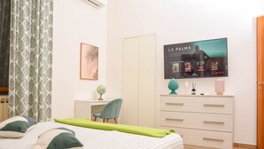 Ein Schlafzimmer mit Bett, Schreibtisch, Stuhl, Fernseher und Kleiderschrank.