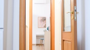 Ein Flur mit einer Holztür, die zu einem Raum mit Schreibtisch und Stuhl führt.