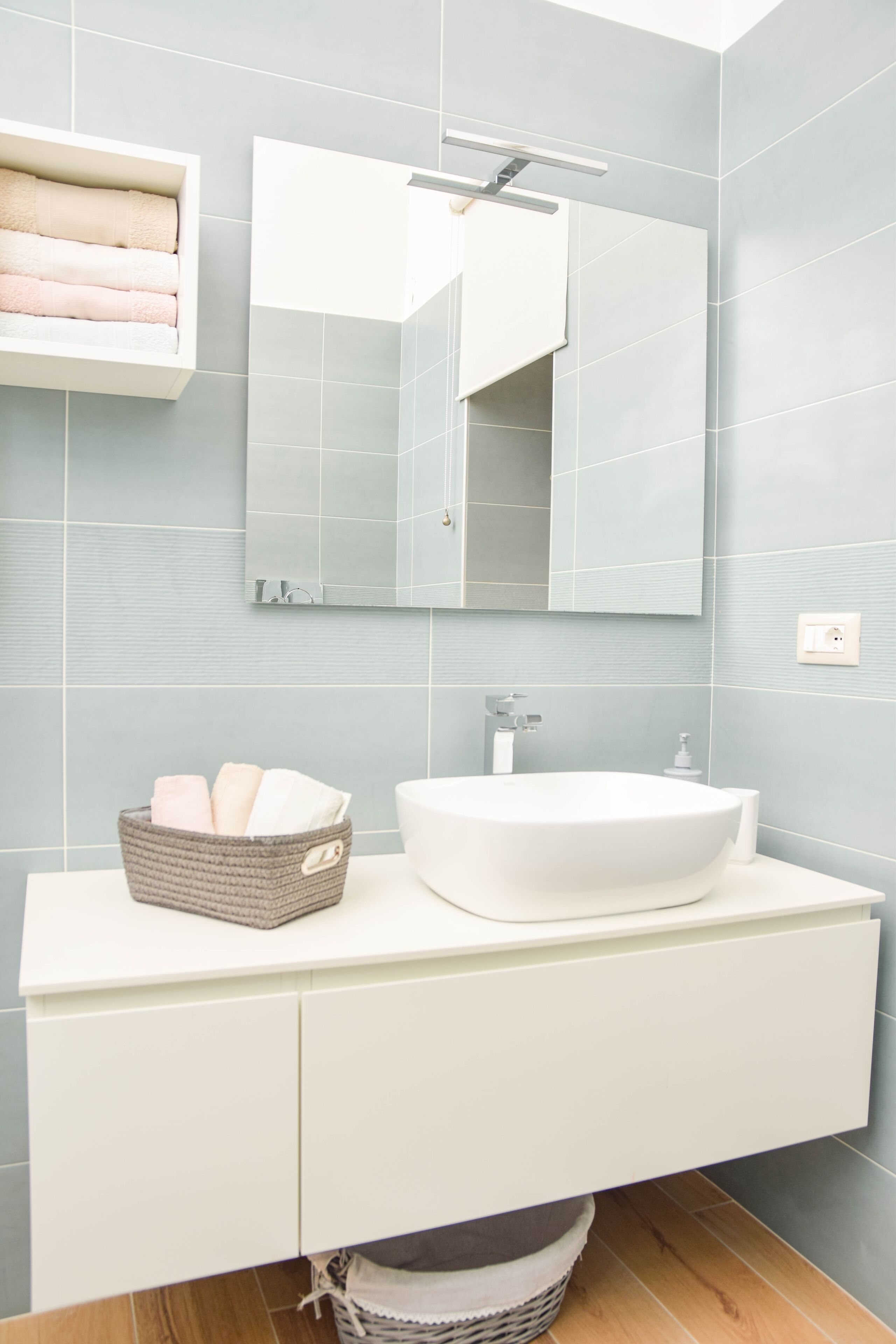 A bathroom with a white sink, a mirror, and a towel rack.
