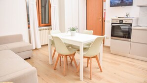 Ein kompakter Wohnraum mit Essbereich, Küchenzeile und Wand-Fernseher.