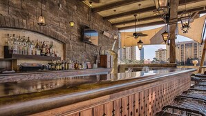 Un bar con parete in pietra, bancone in legno e luci a sospensione.