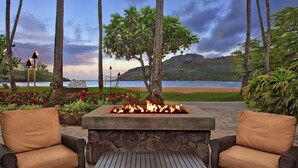 An outdoor seating area with a fire feature, wicker chairs, and a view of the ocean. - Marriott Kauai Lagoons - Kalanipu'u - Luxurious 2-Bedoom - Beachfront resort - Family Friendly (Lihue)